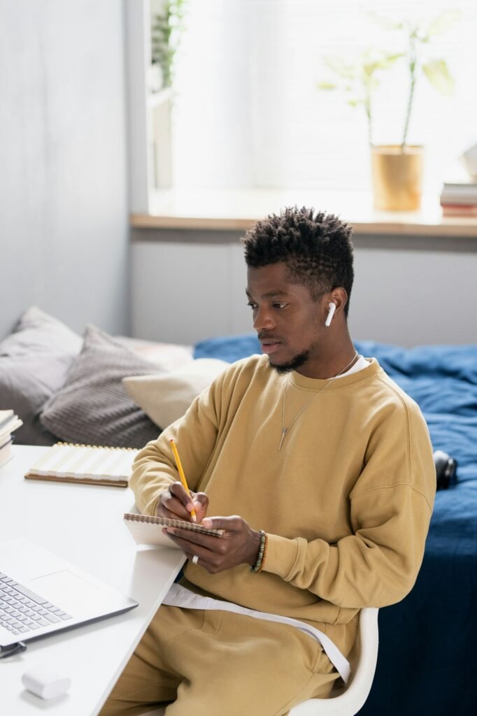 Serious young African student making notes in notepad