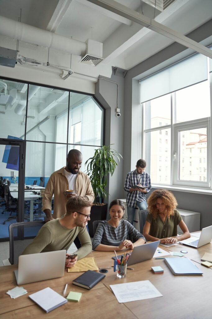 Successful team in coworking space. Vertical shot of multiracial coworkers communicating, sharing